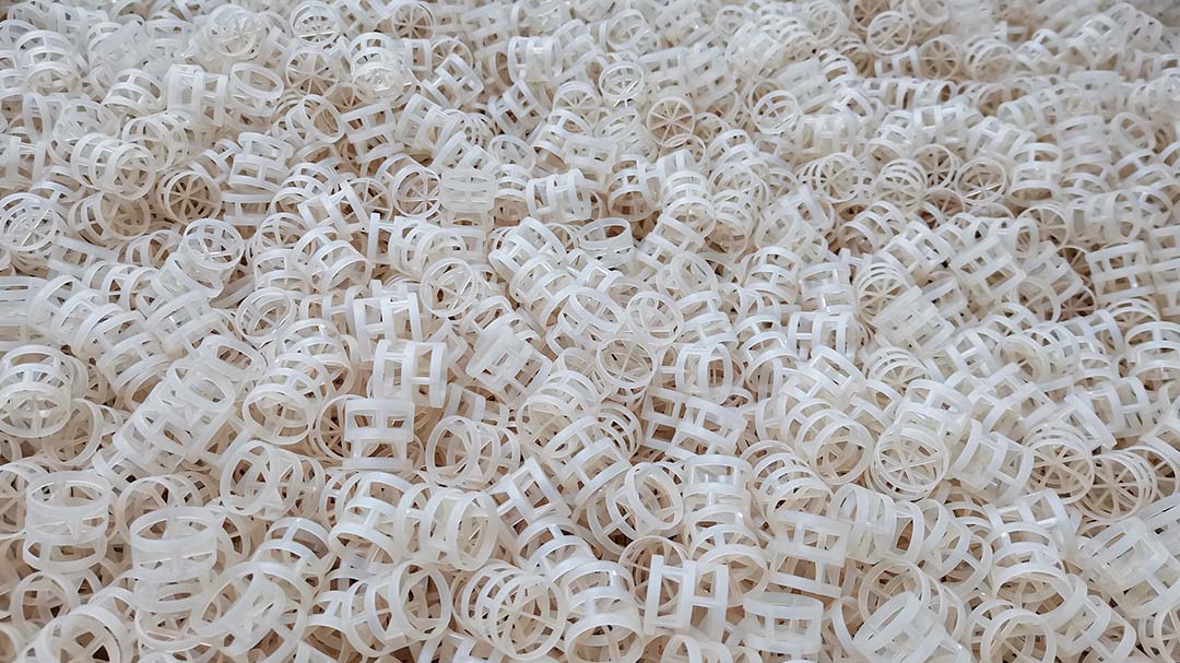 Liquid distributor nozzles above plastic random packing bed